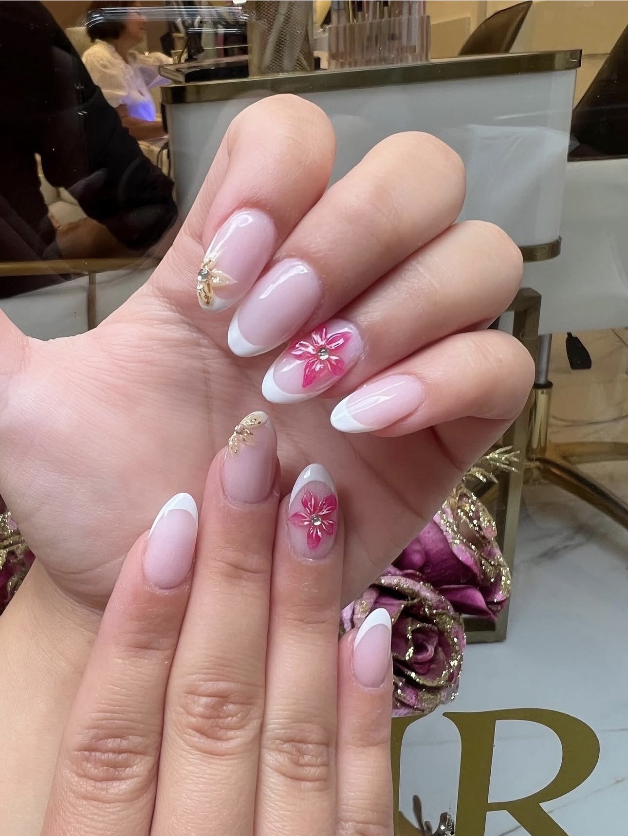 Filigranes Nageldesign mit floralem Motiv und Goldakzenten